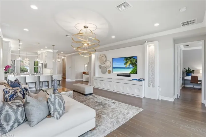 Open-concept living area featuring wood-finish flooring, recessed lighting, and a contemporary chandelier