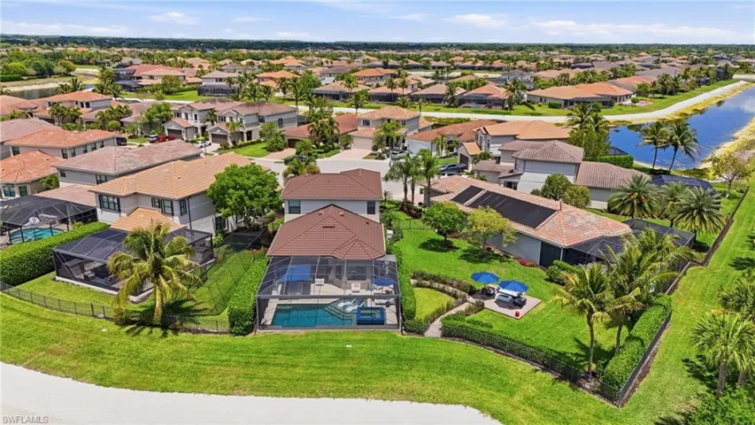 Expansive property featuring a screened-in swimming pool, a large manicured lawn, and mature palm trees