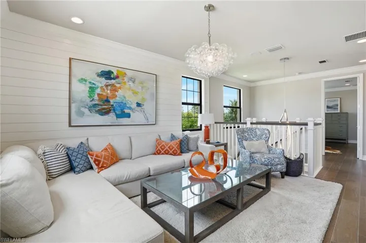 Spacious living area featuring ship-lap accent wall, wood-look flooring, recessed lighting, and a contemporary chandelier