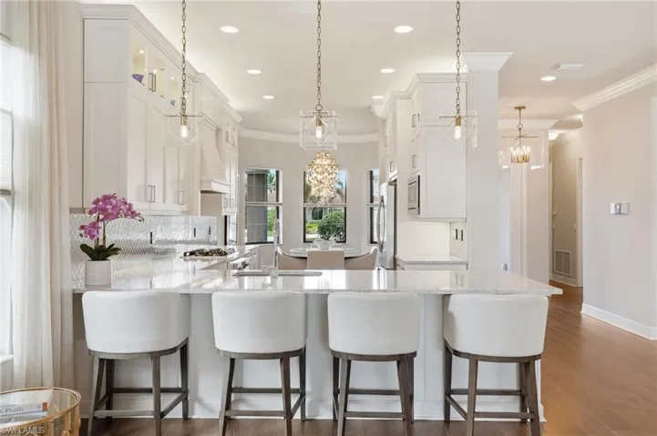 Open-concept kitchen featuring white cabinetry, a large kitchen island with granite countertops, stainless steel appliances, and wood-finish flooring