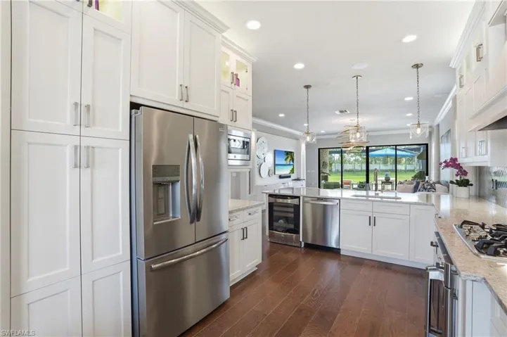 Gourmet kitchen with white shaker cabinetry, stainless steel appliances, granite countertops, and wood-finish flooring