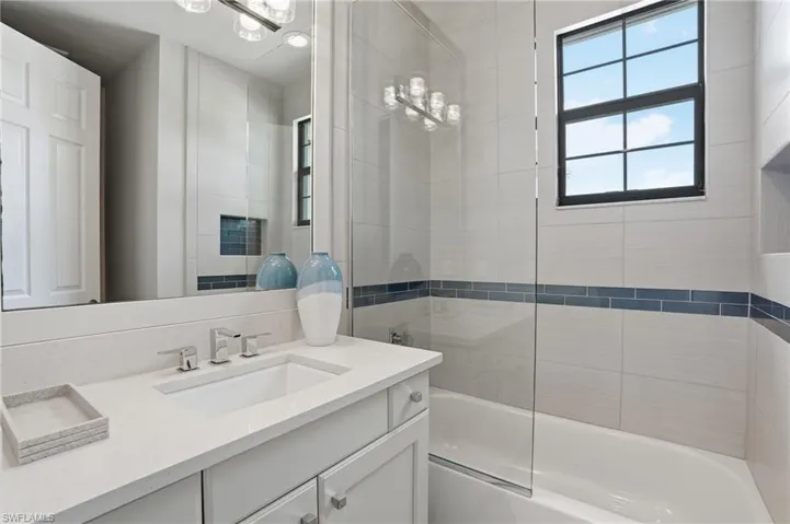 Contemporary bathroom featuring a white vanity with an integrated sink, polished chrome faucet, and a large mirror