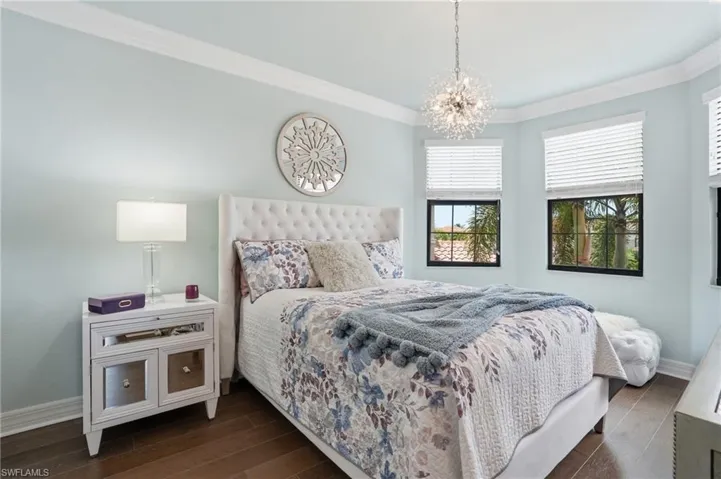 Bedroom featuring wood-finish flooring, bay windows, and crown molding