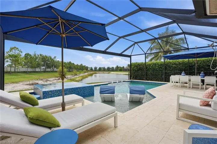Screened pool enclosure featuring a pool with water features, an integrated spa, and a light-colored paver deck