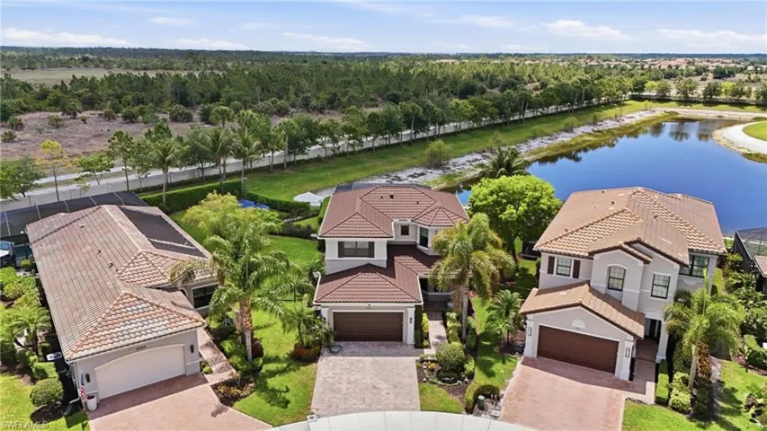 Two-story residence featuring a tile roof, paved driveway, and mature palm trees