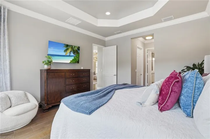 Spacious interior featuring a multi-tiered tray ceiling, recessed lighting, wood-finish flooring, and crown molding