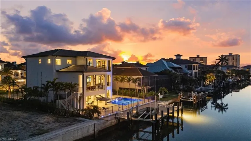 Rear view of property with a patio area, boat lift, a fenced in pool, a water view, and stucco siding