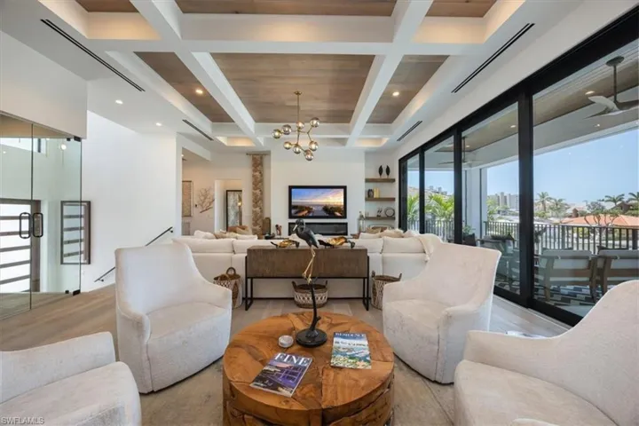 Living area with an inviting chandelier, beamed ceiling, coffered ceiling, and recessed lighting