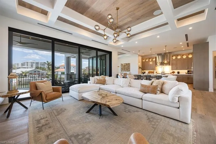 Living area featuring beamed ceiling, coffered ceiling, light wood-type flooring, and a chandelier