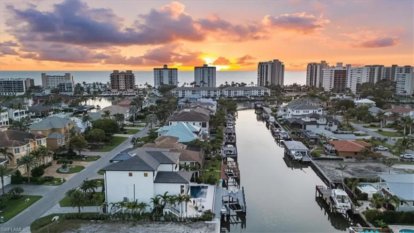Aerial view at dusk featuring a water view and a residential view
