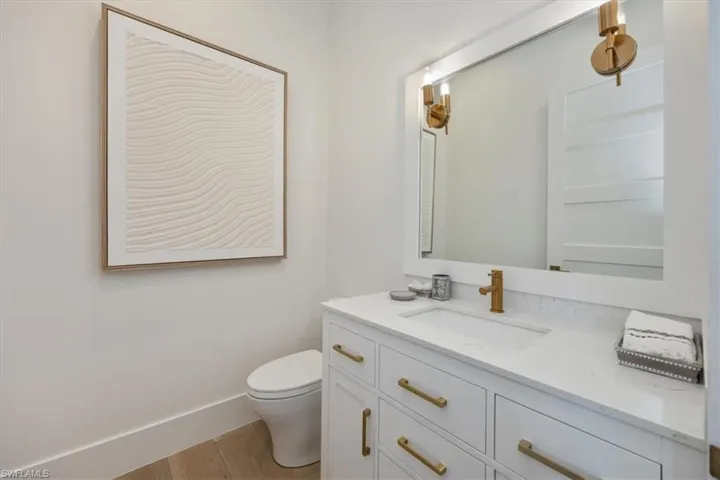 Half bath with toilet, wood finished floors, and vanity
