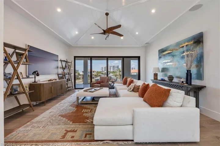 Living room with high vaulted ceiling, ceiling fan, recessed lighting, and wood finished floors