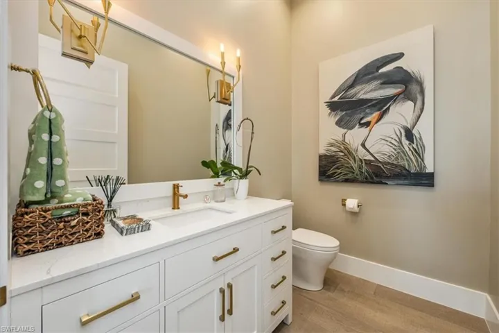 Bathroom featuring vanity, baseboards, wood finished floors, and toilet
