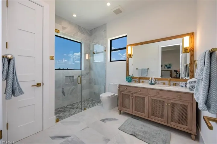 Full bath with visible vents, double vanity, toilet, a sink, and a stall shower