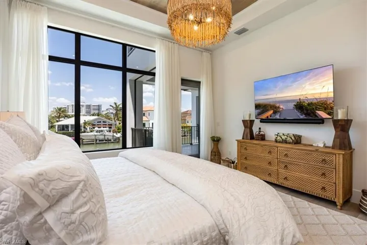 Bedroom with visible vents, access to outside, wood finished floors, and a notable chandelier