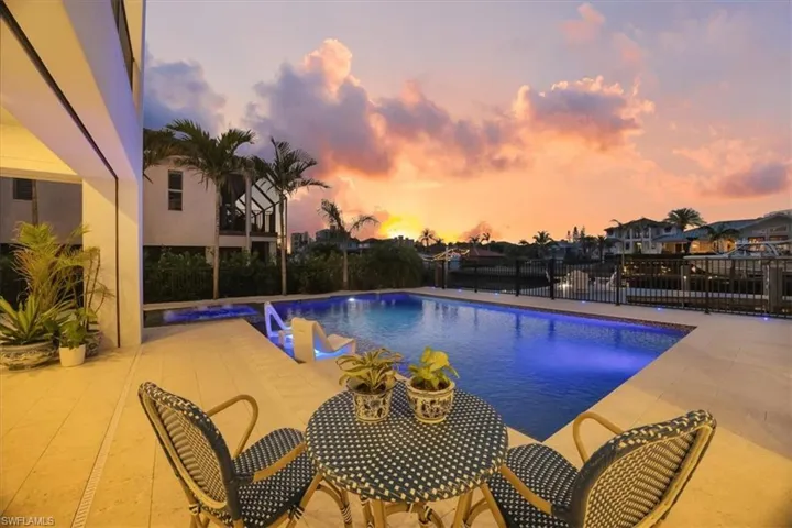 View of pool with a patio, fence, and a pool with connected hot tub