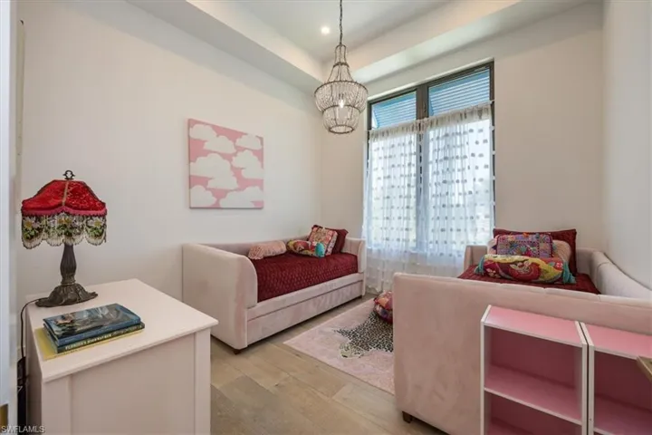 Bedroom with light wood-style floors, a tray ceiling, recessed lighting, and a notable chandelier