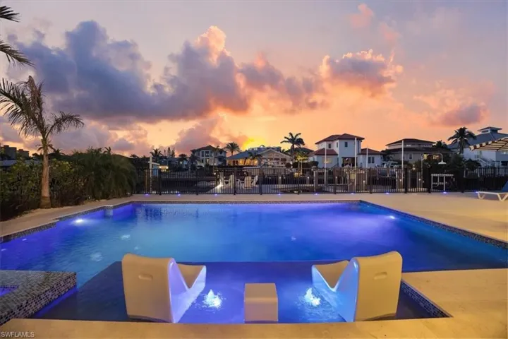 View of swimming pool with a pool with connected hot tub, fence, and a residential view