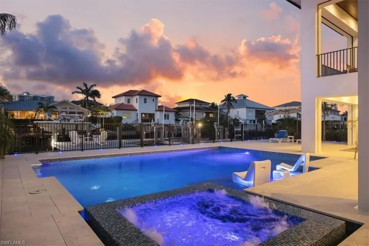 View of swimming pool with fence, a patio, a pool with connected hot tub, and a residential view