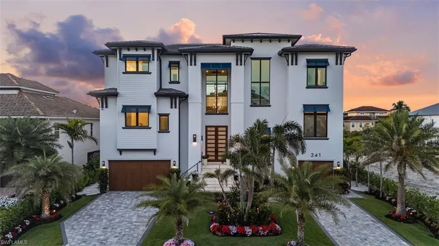 View of front facade with a lawn, decorative driveway, a garage, and stucco siding