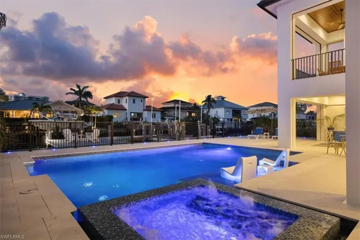 View of pool featuring a residential view, fence, a pool with connected hot tub, and a patio area
