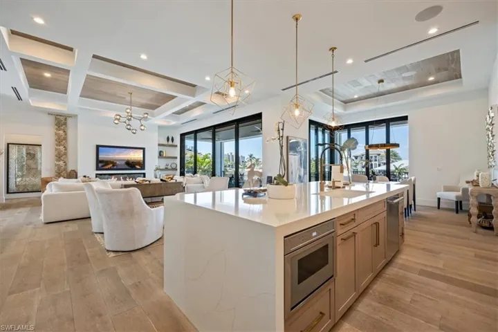 Kitchen with a sink, coffered ceiling, light wood-type flooring, and a notable chandelier