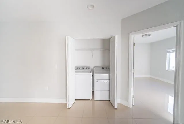 Washroom with light tile patterned flooring and washer and dryer