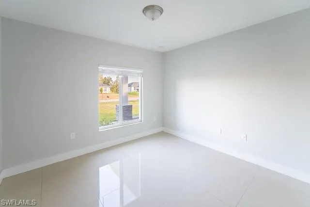 Empty room featuring baseboards and light tile patterned floors