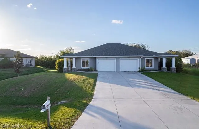 Ranch-style home with a front yard, concrete driveway, stucco siding, and an attached garage