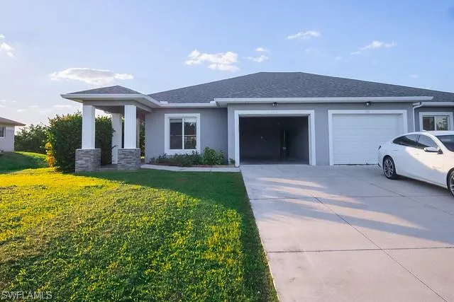 View of front of house with stucco siding, driveway, a garage, and a front yard