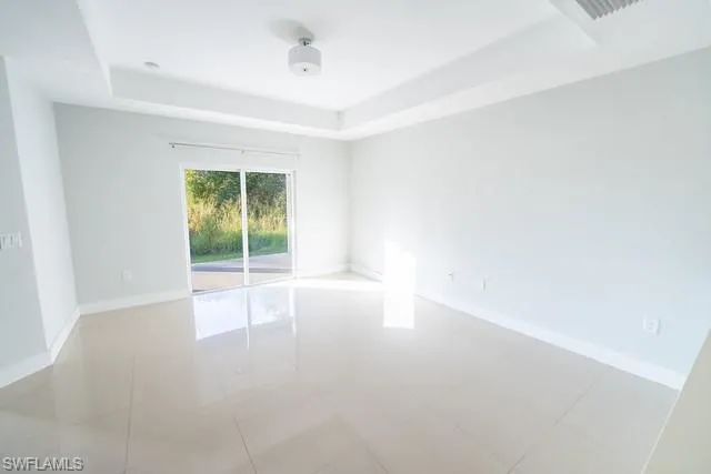 Spare room with a tray ceiling and light tile patterned floors