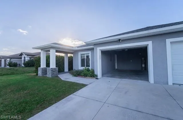 View of front of house featuring stucco siding, driveway, and a front yard