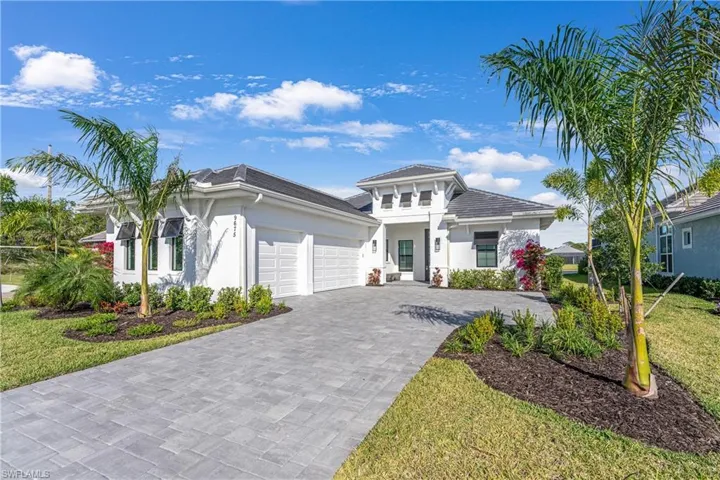 View of front facade with stucco siding, decorative driveway, an attached garage, and a front lawn