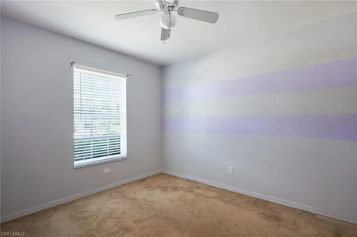 Empty room with ceiling fan and light carpet
