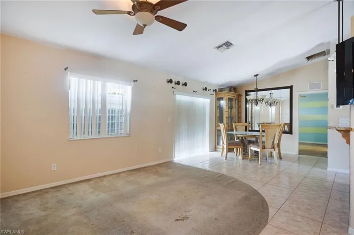 Unfurnished dining area featuring light carpet, ceiling fan with notable chandelier, and lofted ceiling