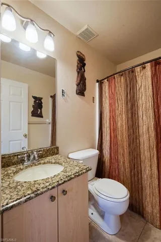 Bathroom featuring vanity, toilet, a textured ceiling, and tile patterned floors