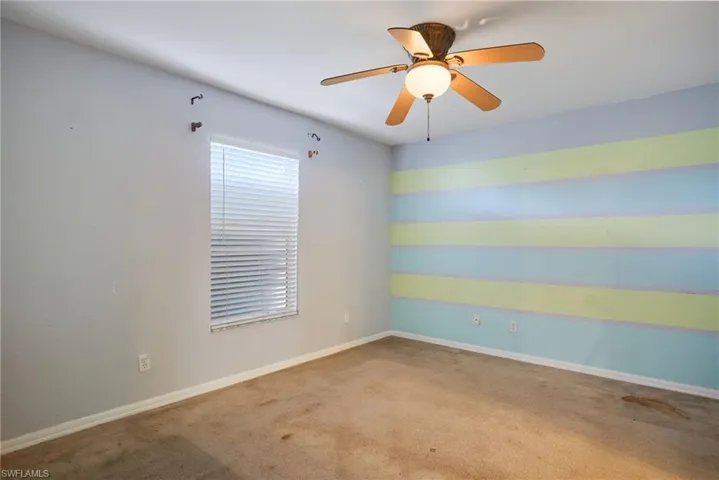 Carpeted spare room featuring ceiling fan