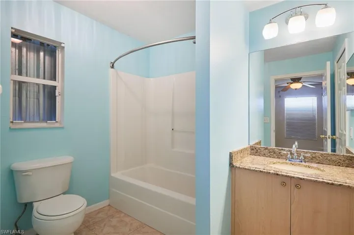 Full bathroom with ceiling fan, vanity, shower / bath combination, tile patterned floors, and toilet