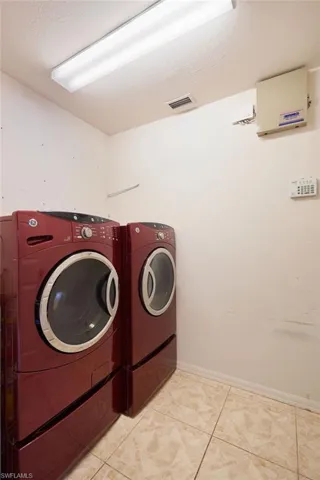 Laundry area featuring a textured ceiling, light tile patterned floors, and washing machine and clothes dryer
