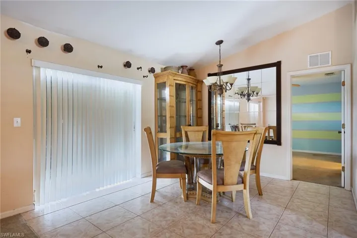 Tiled dining area featuring lofted ceiling and a chandelier