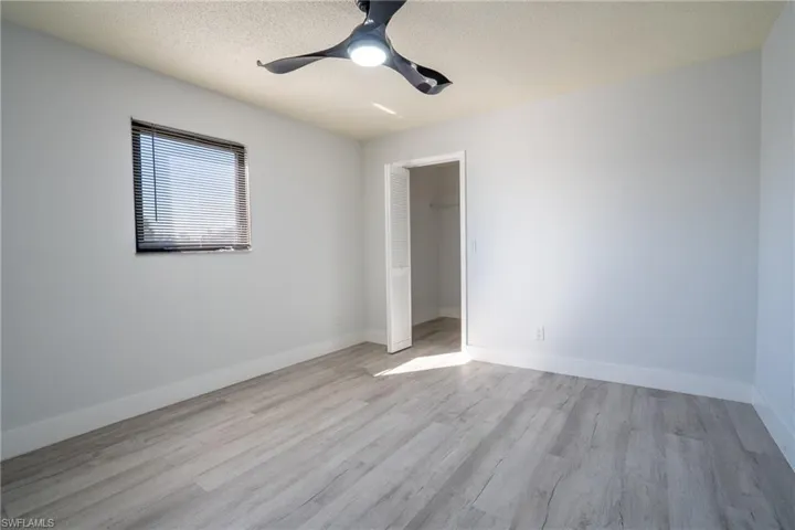 Guest room with ceiling fan, light hardwood / wood-style flooring, and a textured ceiling