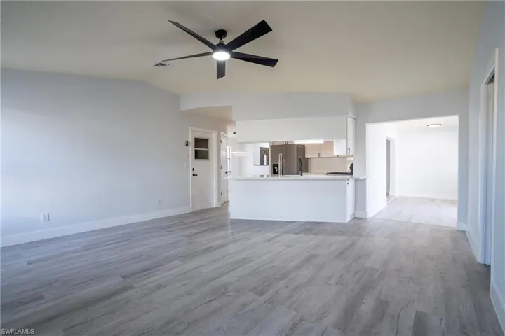 Unfurnished living room with ceiling fan, light hardwood / wood-style floors, and vaulted ceiling