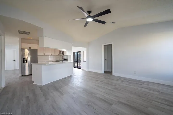 Kitchen featuring sink, white cabinetry, vaulted ceiling, light wood-type flooring, and stainless steel appliances