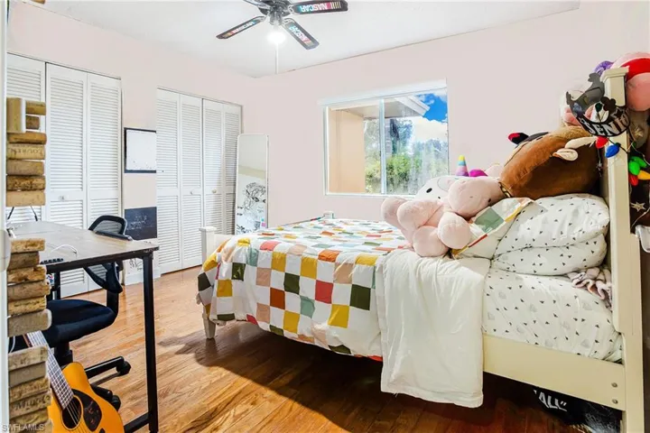 Bedroom featuring multiple closets, light wood-type flooring, a desk, and ceiling fan