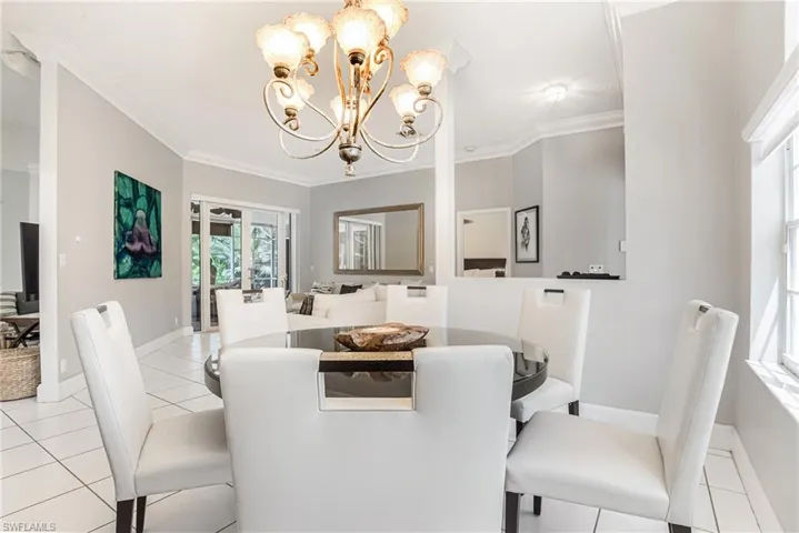 Dining space with light tile patterned flooring, crown molding, and a chandelier