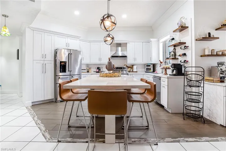 Kitchen featuring white cabinetry, appliances with stainless steel finishes, open shelves, crown molding, and a center island
