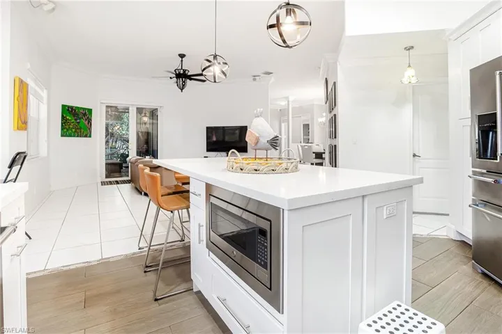 Kitchen featuring white cabinetry, open floor plan, a breakfast bar area, pendant lighting, and stainless steel appliances