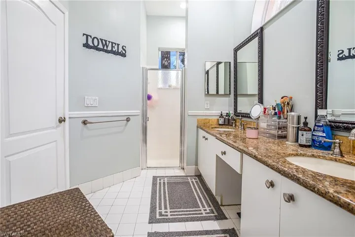 Full bathroom featuring double vanity, a shower stall, and light tile patterned flooring