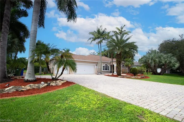 View of front of home with a front lawn, an attached garage, decorative driveway, and stucco siding