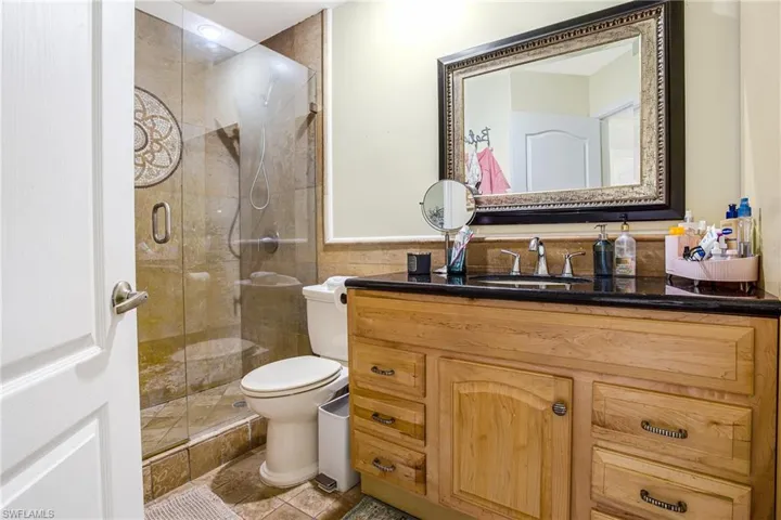 Full bathroom featuring vanity, a shower stall, light tile patterned flooring, and a wainscoted wall